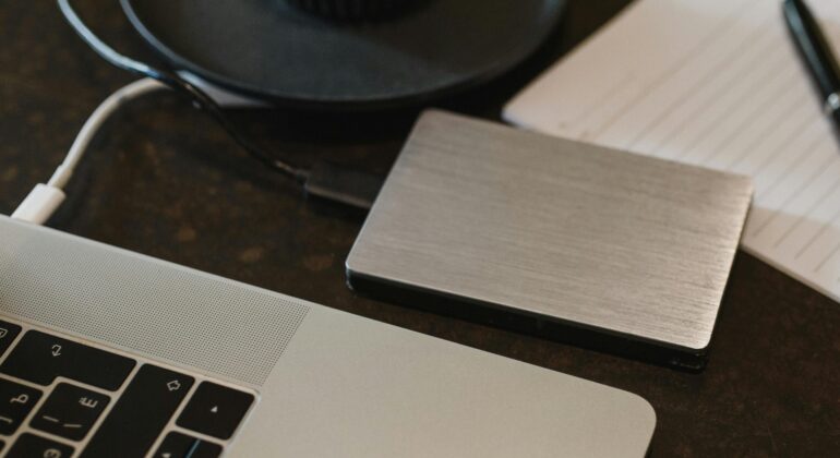 Free Closeup of an external hard drive connected to a laptop with a USB cable on a desk. Stock Photo