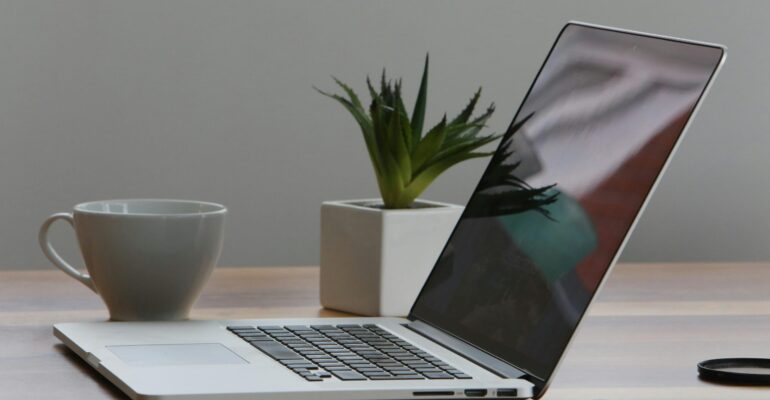 Free Minimalist home office desk with laptop, smartphone, and plant for a modern work environment. Stock Photo