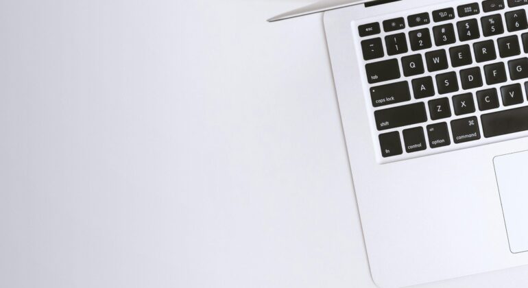 Free Aerial view of a sleek laptop keyboard on a clean, white surface, ideal for tech backgrounds. Stock Photo