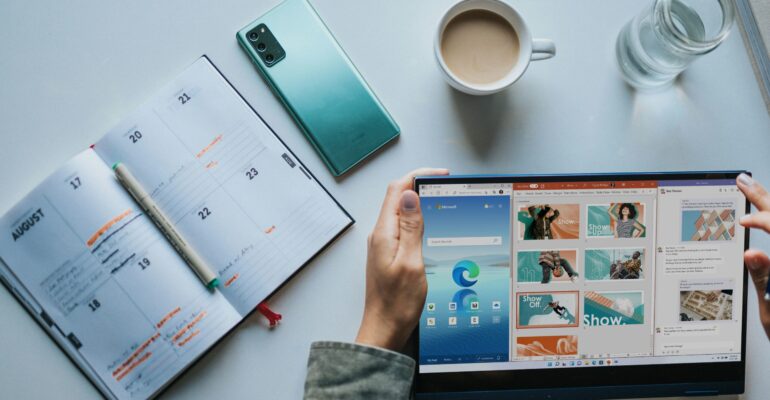 person using Windows 11 computer beside white ceramic mug on white table