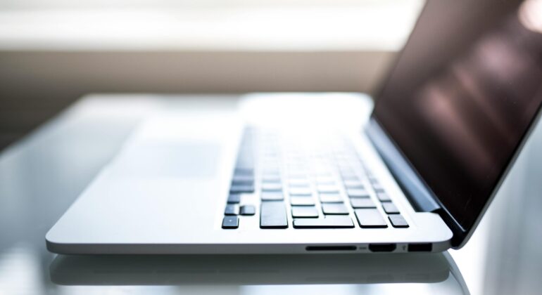 Free Elegant side view of a laptop on a glossy table with natural lighting indoors. Stock Photo