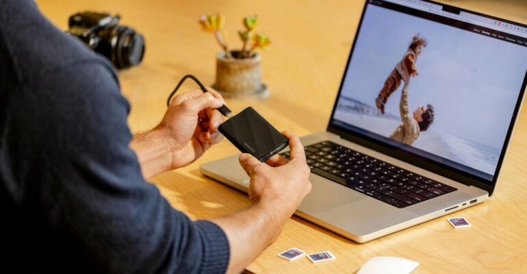 A man sitting at a table with a laptop and cell phone
