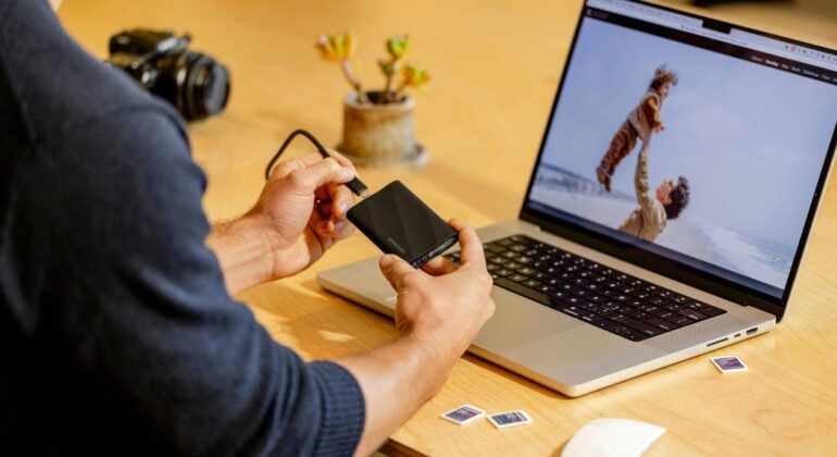 A man sitting at a table with a laptop and cell phone